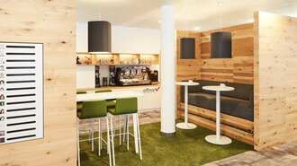 Work-Café Aufbau im Showroom der offino Bürolösungen GmbH in Kempten. An der hinteren Wand eine Küchenzeile mit diversen, modernen Kaffeemaschinen unterschiedlicher Bauart und mit Geschirr gefüllten Hängeregale aus Echtholz. Rechts im Bild eine Sitzgelegenheit mit massivem Echtholz-Rahmen, grauem Polster und matellsicher Fußstütze, davor zwei weiße Bistro-Tischchen. Links ein weißer Hochtisch mit weiß-grünen Barstühlen. Im Vordegrund links hängt eine fiktive Mitarbeiterliste an einer Wand aus Holz.