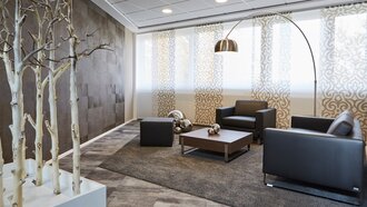 Gemütliche Möbelgruppe für Besprechungen in einem in braun gehaltenen Raum des Showrooms der offino Bürolösungen GmbH in Kempten. Ein Hocker, Ein Sofa, ein Sessel und eine gebogende Stehlampe werden von einem Kunstobjekt aus Birkenstämmen und einem weißen Sockel am linken Bildrand in Szene gesetzt.